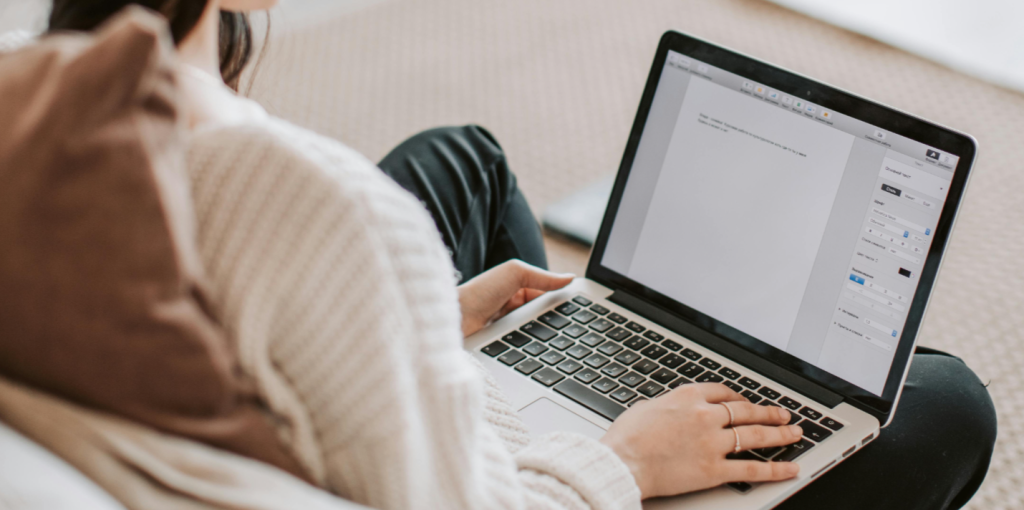 Alt text: "Person in white sweater using laptop to draft podcast summary with hands on keyboard and pillow in background Creatorpoint – Creator Knowledge, Simplified. The best resources, podcast summaries, and learning for creators.