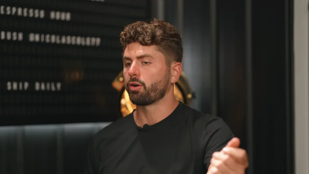 Curly-haired person with beard in black shirt speaks and gestures, dark background with blurred text on making money writing, subtle lighting elements. Creatorpoint – Creator Knowledge, Simplified. The best resources, podcast summaries, and learning for creators.