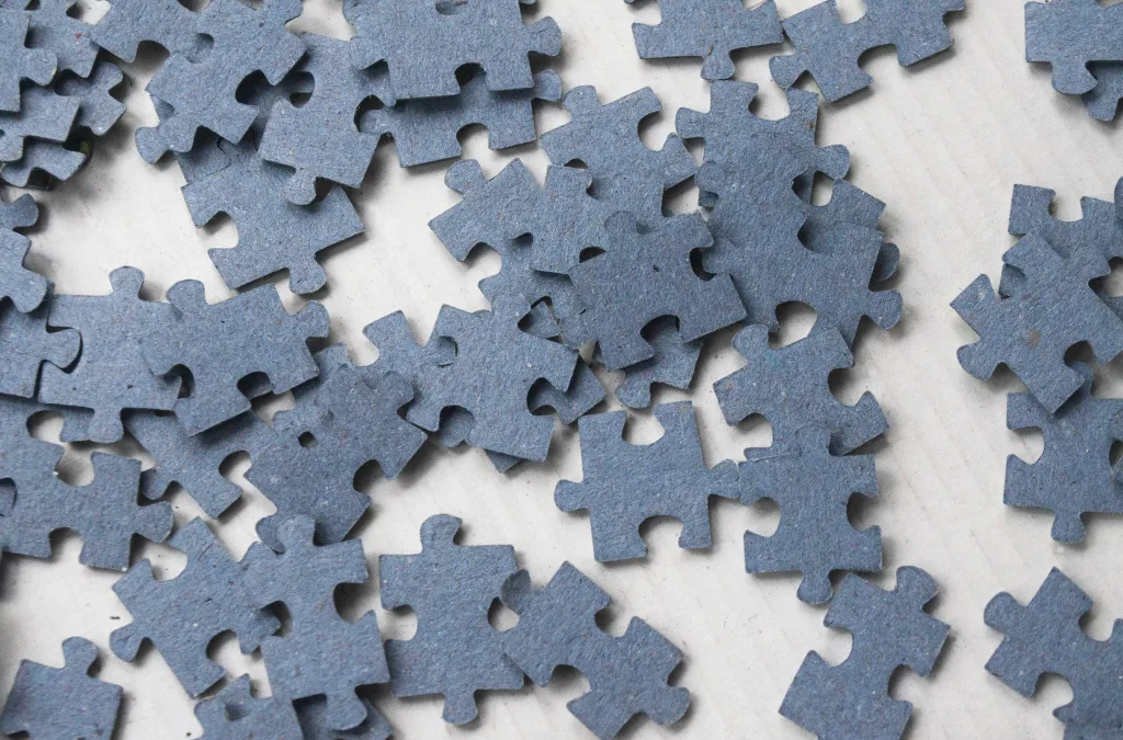 Alt text optimized for SEO: "Close-up of dark blue jigsaw puzzle pieces scattered on a light surface, representing brainstorming and idea assembly for podcasts at CreatorPoint. Creatorpoint – Creator Knowledge, Simplified. The best resources, podcast summaries, and learning for creators.