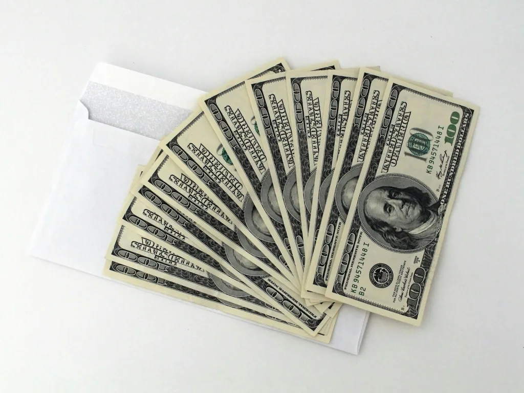 Hundred dollar bills fanned out in front of a white envelope on a white background, symbolizing the financial rewards of gaining YouTube sponsorship. Creatorpoint – Creator Knowledge, Simplified. The best resources, podcast summaries, and learning for creators.