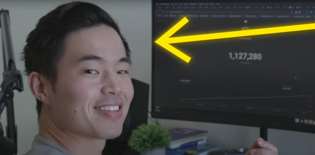 Person smiling and pointing at a computer screen displaying 1,127,280 views on starting a YouTube channel. Yellow arrow highlights the achievement. Desk features a small plant and books. Keywords: YouTube success milestone, video tutorial growth, digital achievement celebration. Creatorpoint – Creator Knowledge, Simplified. The best resources, podcast summaries, and learning for creators.