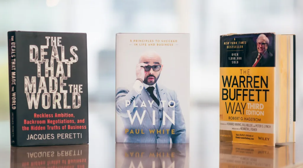 Books to inspire solo business ideas: "The Deals That Made the World" by Jacques Peretti, "Play to Win" by Paul White, "The Warren Buffett Way" by Robert G. Hagstrom. Ideal for entrepreneurs seeking top reads for success strategies and innovation insights. Blurred background setting. Creatorpoint – Creator Knowledge, Simplified. The best resources, podcast summaries, and learning for creators.