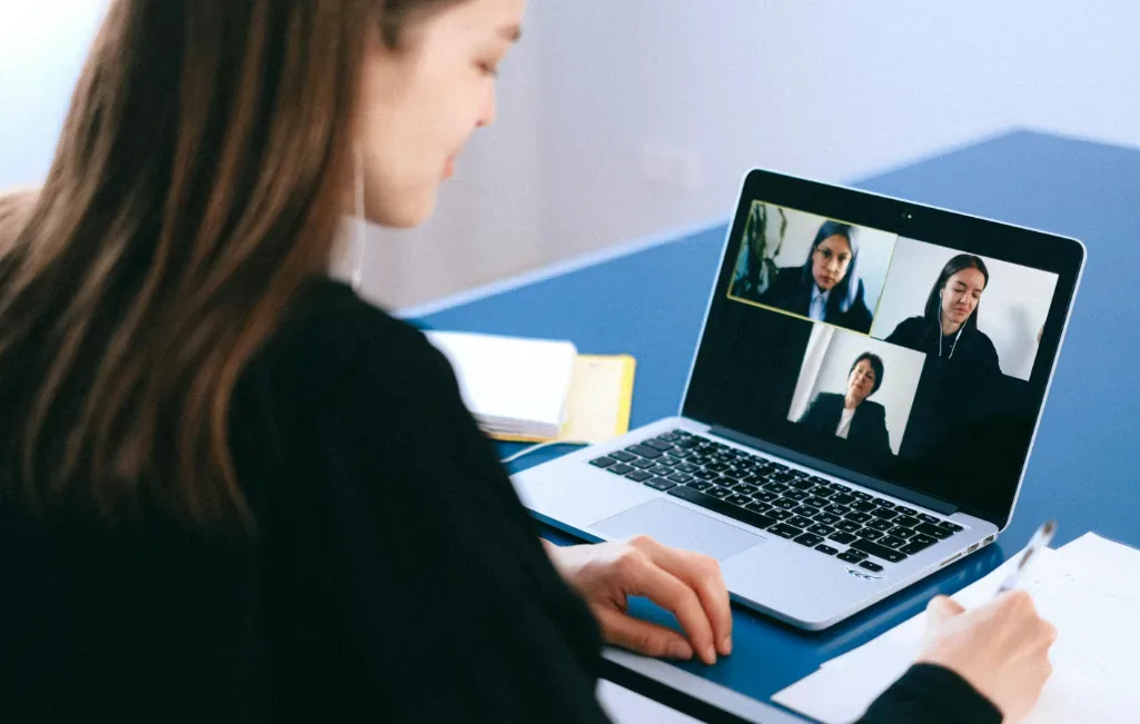 Woman in office workspace on a video call discussing digital product ideas with three participants. She takes notes with pen and paper, capturing innovative thoughts. Engaged in remote work meeting via laptop, the setting is a professional or home office environment focused on creativity and collaboration. Creatorpoint – Creator Knowledge, Simplified. The best resources, podcast summaries, and learning for creators.