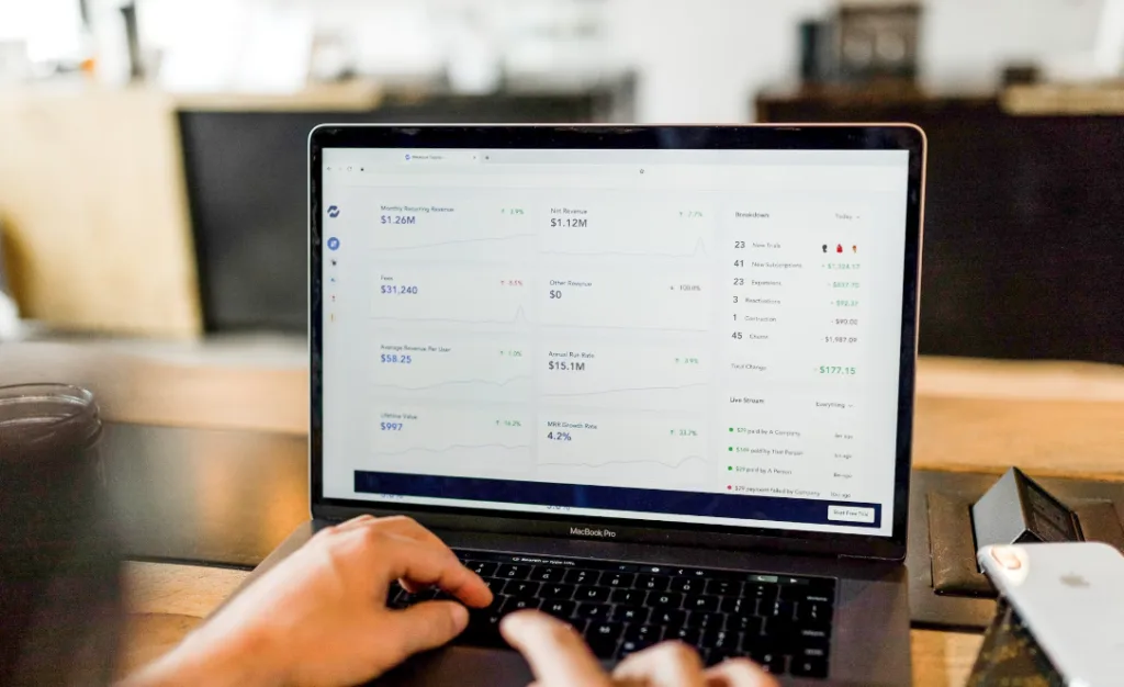 Alt text: "User on laptop with financial dashboard exploring innovative digital product ideas. Screen features monthly recurring revenue, customer metrics, projections. Laptop on wooden desk signifies inspiration and insight in business development. Creatorpoint – Creator Knowledge, Simplified. The best resources, podcast summaries, and learning for creators.