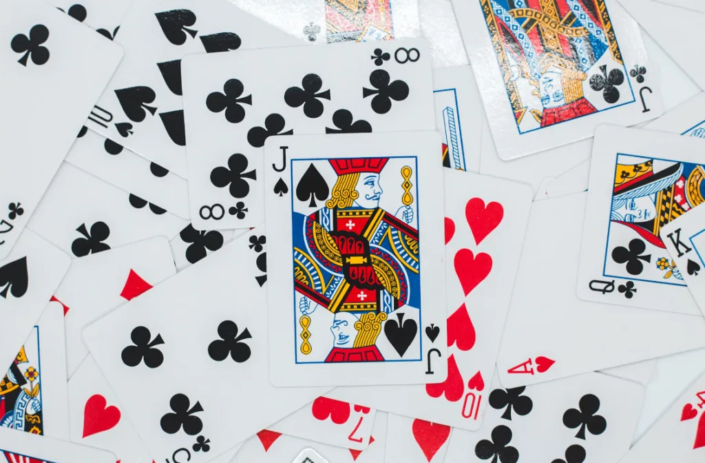 Alt text: "A disordered pile of playing cards with distinct suits—spades, hearts, clubs, diamonds. Face cards like kings and jacks visible. Inspiring faceless YouTube channel ideas on captivating card tricks and expert shuffling techniques for enthusiasts seeking engaging content. Creatorpoint – Creator Knowledge, Simplified. The best resources, podcast summaries, and learning for creators.