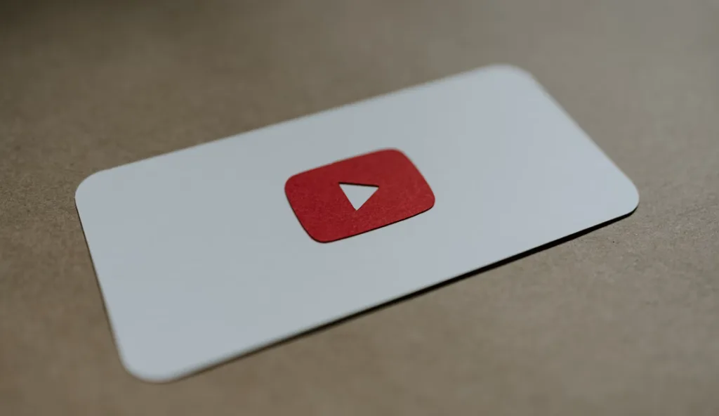 YouTube logo red play button on white rectangular card, sitting on brown surface. Discover essential YouTube tips and tricks. Elevated card promotes optimizing videos, boosting views, increasing subscribers, and mastering YouTube algorithms for successful channel growth and engagement. Creatorpoint – Creator Knowledge, Simplified. The best resources, podcast summaries, and learning for creators.