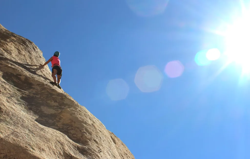 Helmeted climber in vivid attire ascends rugged rock face, embodying faceless YouTube channel ideas. Sunlit scene with clear sky and lens flares highlights action and safety gear for outdoor adventure enthusiasts seeking visual inspiration and safety tips. Perfect SEO image description under 350 characters. Creatorpoint – Creator Knowledge, Simplified. The best resources, podcast summaries, and learning for creators.