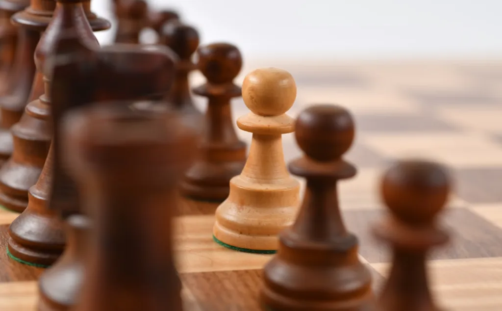 Close-up of a white pawn on a chessboard symbolizing strategic YouTube channel ideas for faceless content creators. Blurred dark pieces surround it, suggesting competition and creativity. Alternating light and dark squares hint at the beginning of an exciting journey in digital content creation. Creatorpoint – Creator Knowledge, Simplified. The best resources, podcast summaries, and learning for creators.