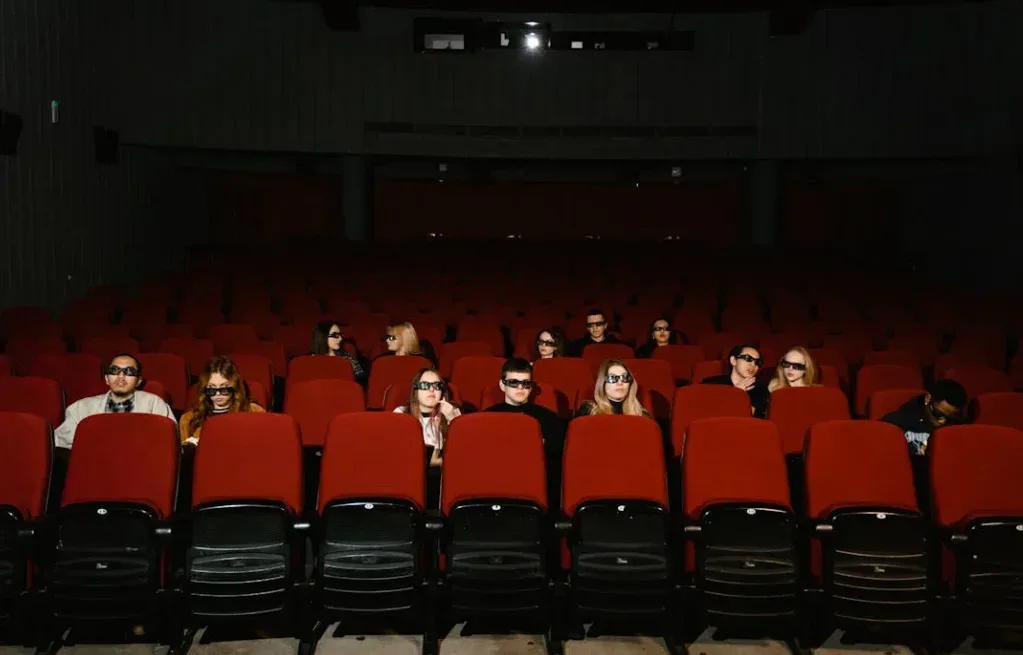 People in 3D glasses sit in a nearly empty movie theater, echoing a YouTube Shorts tutorial on gaining views. The audience focuses on the screen surrounded by rows of red chairs in the dimly lit venue. Creatorpoint – Creator Knowledge, Simplified. The best resources, podcast summaries, and learning for creators.